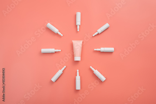 Pink cream tube surrounded by white applicators on a peach surface