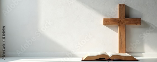 Wooden cross stands near opened bible. Minimalist design on white background with soft shadows. Spiritual composition provides copy space. Suitable for church events, sermon series announcements