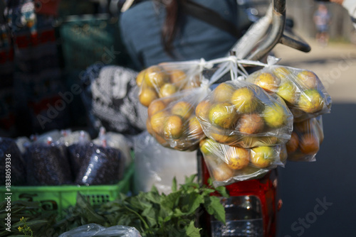 Bags of fresh jujube fruit hanging for sale from motorcycle at vibrant outdoor street market. local food vendor sells healthy produce and traditional snacks in an authentic scene