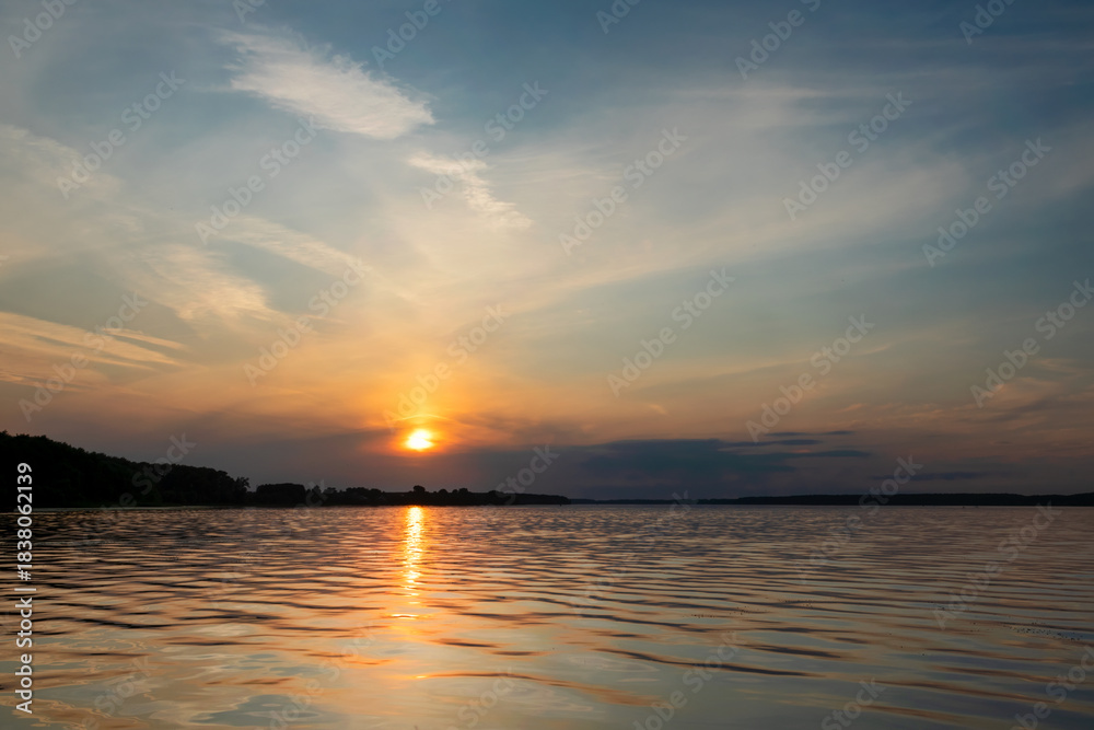 Fototapeta premium Sunset and its reflection in the water and waves of the reservoir