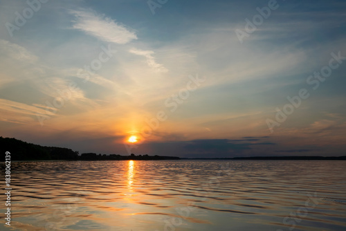 Sunset and its reflection in the water and waves of the reservoir