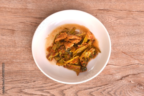 spicy stir fried Thai morning glory with slice fat pork belly in curry sauce on plate 