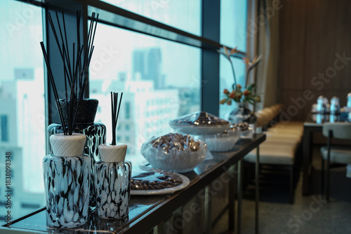 Modern Saudi interior detail featuring elegant glass incense diffusers, scented reeds, and decorative jars by a window. A refined lifestyle scene reflecting Saudi hospitality and contemporary home dec