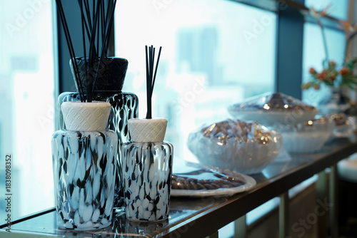 Modern Saudi interior detail featuring elegant glass incense diffusers, scented reeds, and decorative jars by a window. A refined lifestyle scene reflecting Saudi hospitality and contemporary home dec