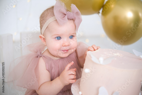 little beautiful blue-eyed girl celebrates her first birthday and tastes her first birthday cake