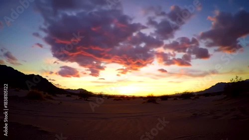 Vibrant Desert Sunset with Fiery Clouds and Silhouetted Mountains.