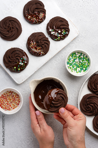 Process of making Christmas chocolate sable cookies. Covered in chocolate and sprinkled with colorful sprinkles. A festive New Year's dessert. Top view