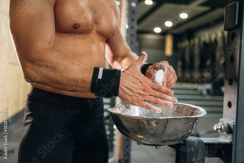 Foto Fitness man is rubbing his hands with chalk, specifically magnesium carbonate
