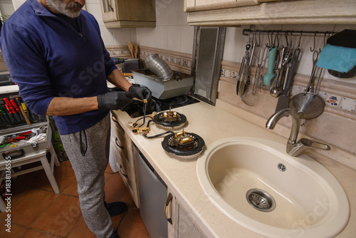 Technician connecting motor wires in a kitchen extractor hood during appliance repair, using tools and gloves for safe, precise maintenance on the countertop.