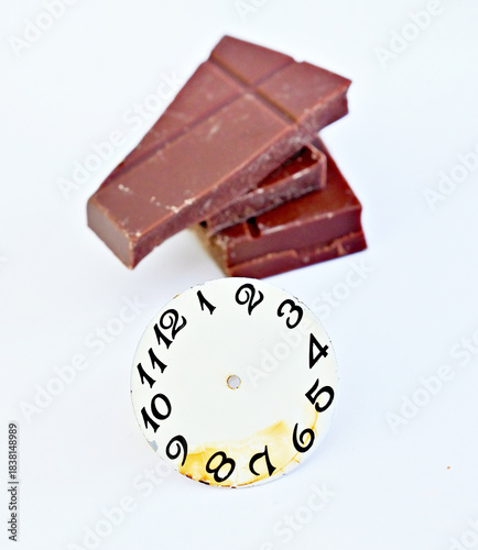 numbers on vintage wrist watch on front of chocolate pieces, food and time concept