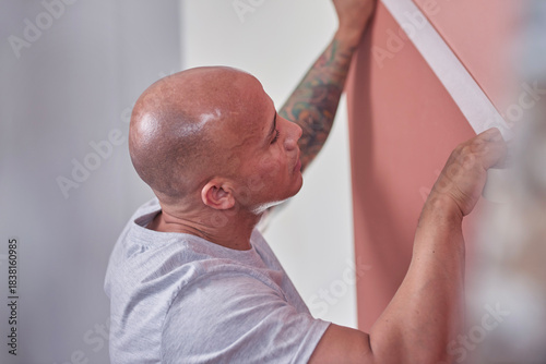 Focused Man Applies Wallpaper on Fresh Wall During Home Improvement Project