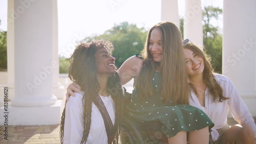 three multiracial friends one disabled in a wheelchair enjoying a sunny day outdoors showcasing joy and connection in a picturesque location during golden hour