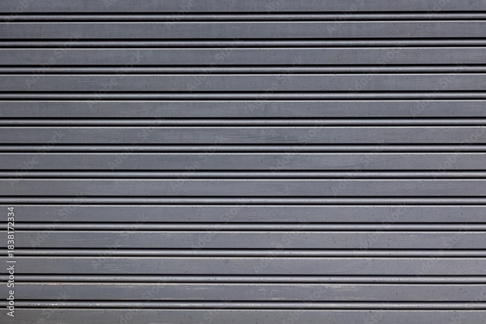 Obraz premium Close-up of a metal shutter showing its grey, gritty surface and worn, textured finish.