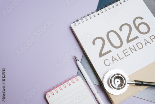 Business concept. 2026 calendar with stethoscope and pen on purple background, medical planning and organization concept with blank notebook for notes