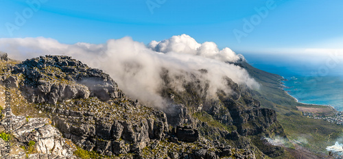 A panorama view of clouds coming over the Twelve Apostles mountain range from the summit of Table mountain, South Africa in springtime
