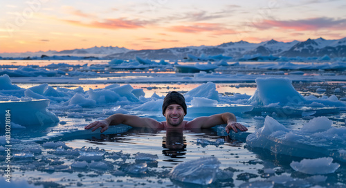 Smiling man swimming in ice cold water with glaciers during sunset. Winter swimming in frozen arctic sea. Cold therapy and healthy lifestyle concept