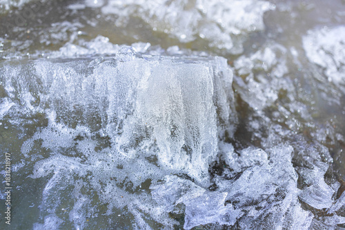 Close-up view of intricate ice formations on a water surface, showcasing bubbles and textured patterns, creating a captivating winter scene filled with natural beauty and detail