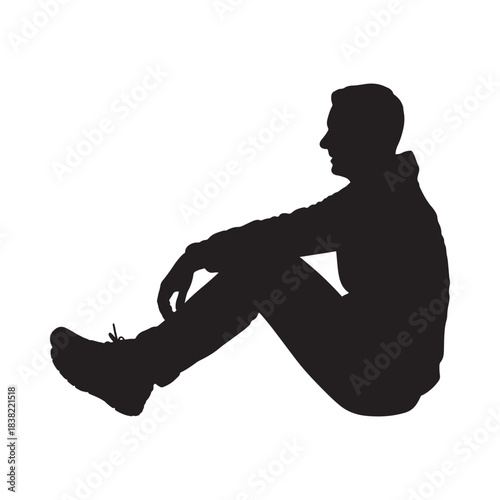 A solitary figure sits in silhouette head resting on knees lost in thought