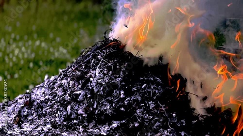 dangerously hot orange and red flames with dense black smoke consuming wood and embers