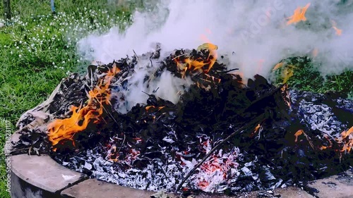 dangerously hot orange and red flames with dense black smoke consuming wood and embers