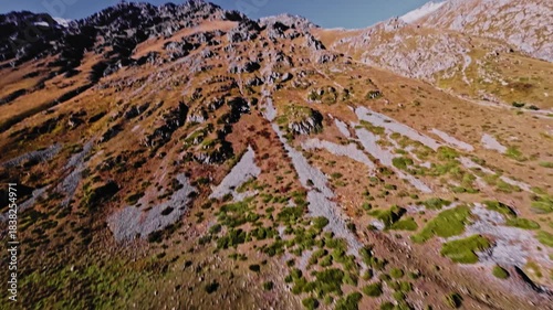 Aerial view of a FPV UAV pursuing high in the mountains on a sunny day. Tracking and pursuing a self-assembled drone.
