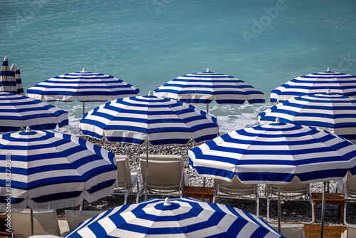 Blue and white striped parasols on the beach at Promenade des Anglais, Nice, France