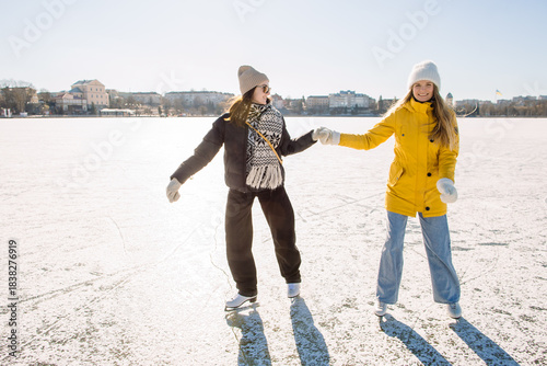 Two young women enjoying winter ice skating on frozen lake