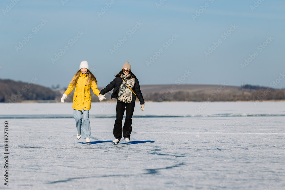 Fototapeta premium Young women ice skating on frozen lake