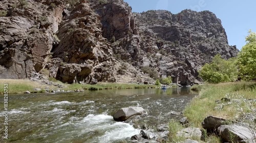 Wide shot of the Gunnison River flowing through rocky Black Canyon under a clear blue sky.