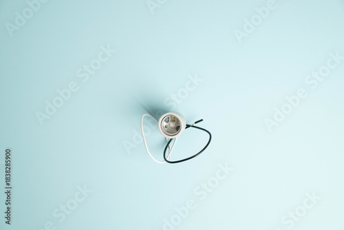 Top view of a new, replacement light socket with white and black wires, on bright blue background