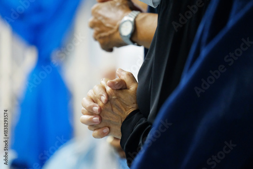 Close-up of a believer clasping their hands in prayer during worship. Soft lighting and added film grain create a classic, emotional atmosphere. Suitable for themes of faith, spirituality, devotion, a