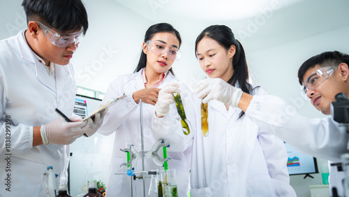 Scientists collaborate in a modern laboratory, closely examining algae samples in test tubes as part of sustainable biotechnology research focused plant science, ecology, and environmental innovation
