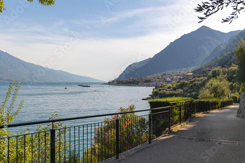 Panoramic view of Limone sul Garda, Lombardy, Italy. A picturesque pedestrian path runs along the blue waters of Lake Garda.