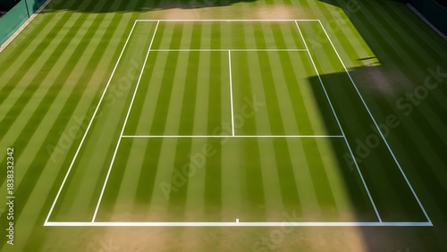 Overhead view of a pristine green grass tennis court on a sunny day with clear white lines for professional sports competition and outdoor recreation activities