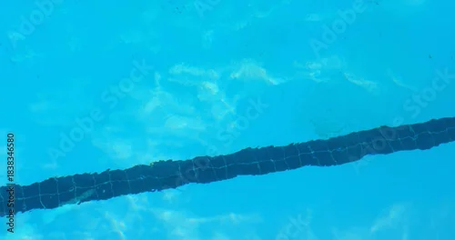 Fototapeta Showing mosaic-tiled lane marker running diagonally across pool, with rippling bright reflections