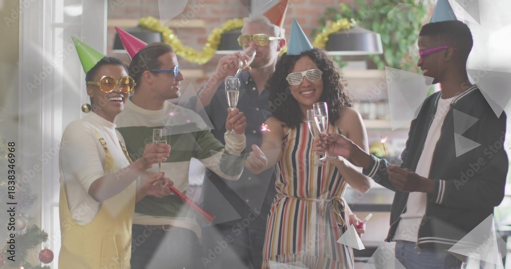 Obraz premium Clinking six adults lifting champagne flutes in home kitchen, wearing cone hats and shutter shades