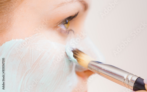 Girl apply green mud mask to face