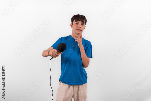 young casual dressed Gen Z entertainer influencer white male host model teenage boy with microphone for singing, presenting and interviewing for social media channel. plain background studio setting