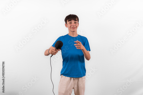 young casual dressed Gen Z entertainer influencer white male host model teenage boy with microphone for singing, presenting and interviewing for social media channel. plain background studio setting