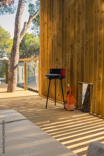 Domestic barbecues with charcoal bag on a wooden building terrace on a holiday apartment in the forest in Costa Brava Camping, Catalonia