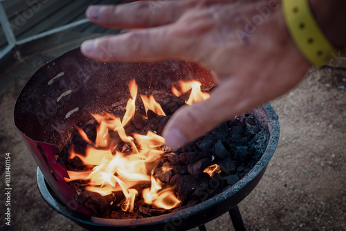 Hand testing the heat of a burning domestic barbecue made of charcoal