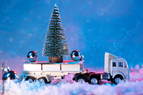 A toy truck carries a small Christmas tree, Christmas and New Year holiday background