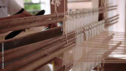 Woman weaving silk fabric on a traditional handloom using ancient weaving techniques, surrounded by nature, Cambodia, Siem Reap.