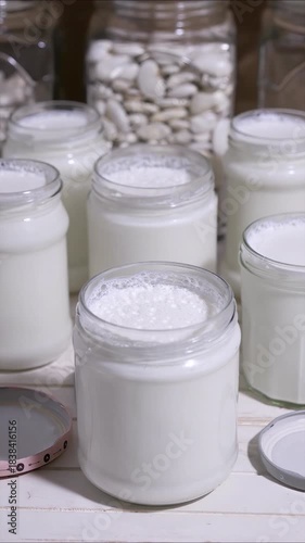 natural yoghurt in glass jars handmade at home fermenting milk with lactobacillus creating a probiotic to take care of the health of our intestine, 4k food video footage 
