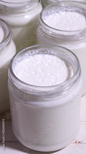 natural yoghurt in glass jars handmade at home fermenting milk with lactobacillus creating a probiotic to take care of the health of our intestine, 4k food video footage 
