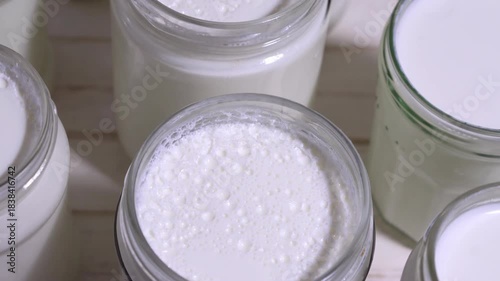 natural yoghurt in glass jars handmade at home fermenting milk with lactobacillus creating a probiotic to take care of the health of our intestine, 4k food video footage 
