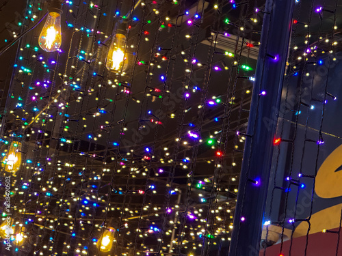 Colorful Christmas lights hanging in glowing mesh installation. Festive ambience, winter night sparkle, joyful holiday mood, magical illumination and celebration atmosphere
