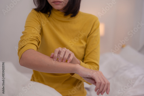 Close-up of a woman scratching her forearm, showing symptoms of itchy skin, allergy, irritation, or dermatitis, concept of skin problems, allergic reaction, and personal health care at home.