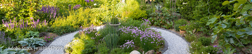 Winding gravel path through blooming garden landscaping - pano