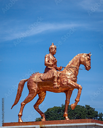 Shining orange colored statue of Nadaprabhu Kempegowada , sitting on a horse in front of Vidhan Soudha, Bangalore, India